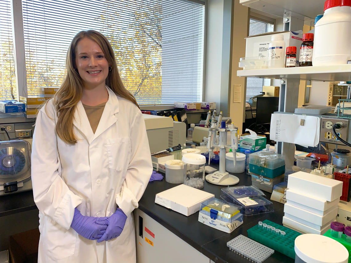 Dana Lowry standing in a lab next to her equipment.